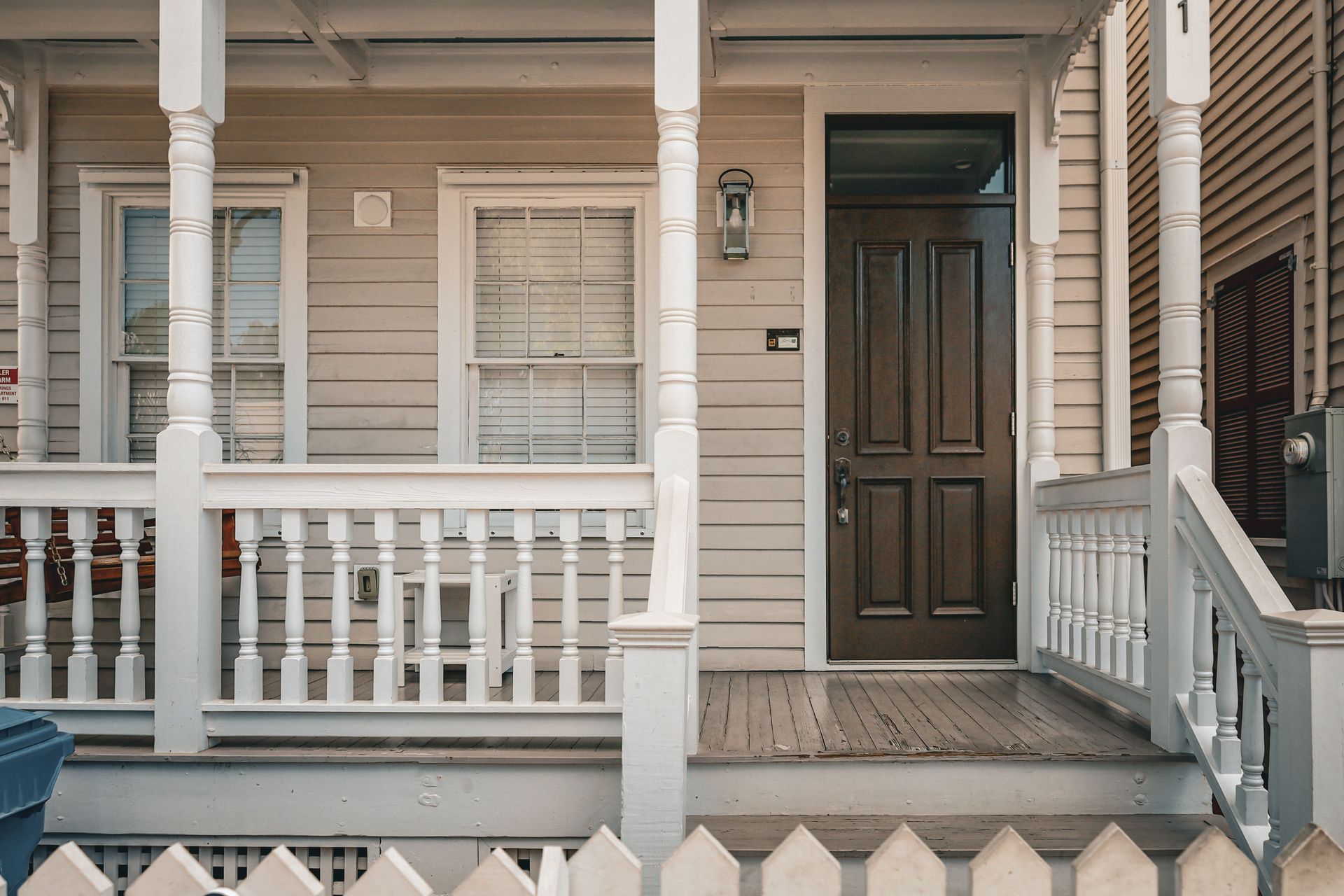 A classic wooden house porch with a decorative entrance and picket fence.